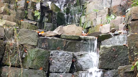 Natural-flowing-stone-waterfall-cascading-down-blocks-of-cut-rock-close-up