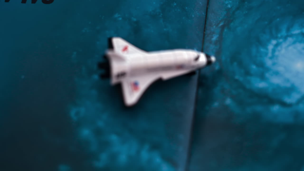 Close up of a miniature toy space shuttle placed on a blue cosmic galaxy backdrop
