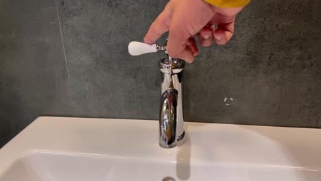 un primer plano de un grifo de agua con un hermoso lavabo blanco