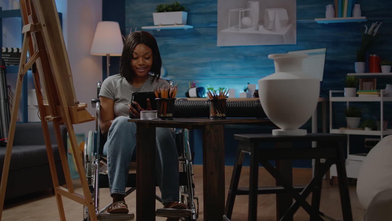 Young black artist in wheelchair using digital tablet