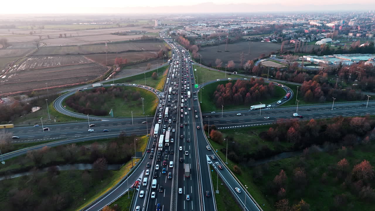 Genişleyen şehir manzarasında alacakaranlıkta yoğun otoyol trafiğinin havadan görünümü