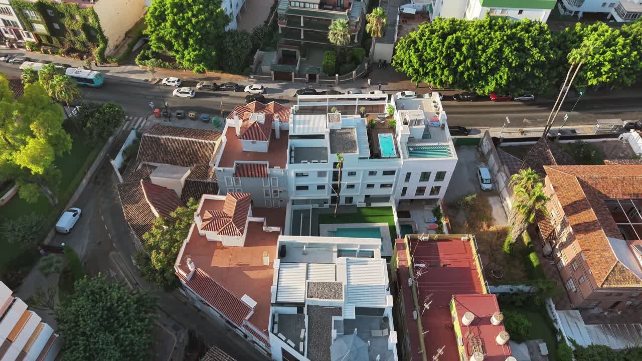 Aerial fly over seaside neighborhood with residential blocks and coastal trees near the beach, Spain