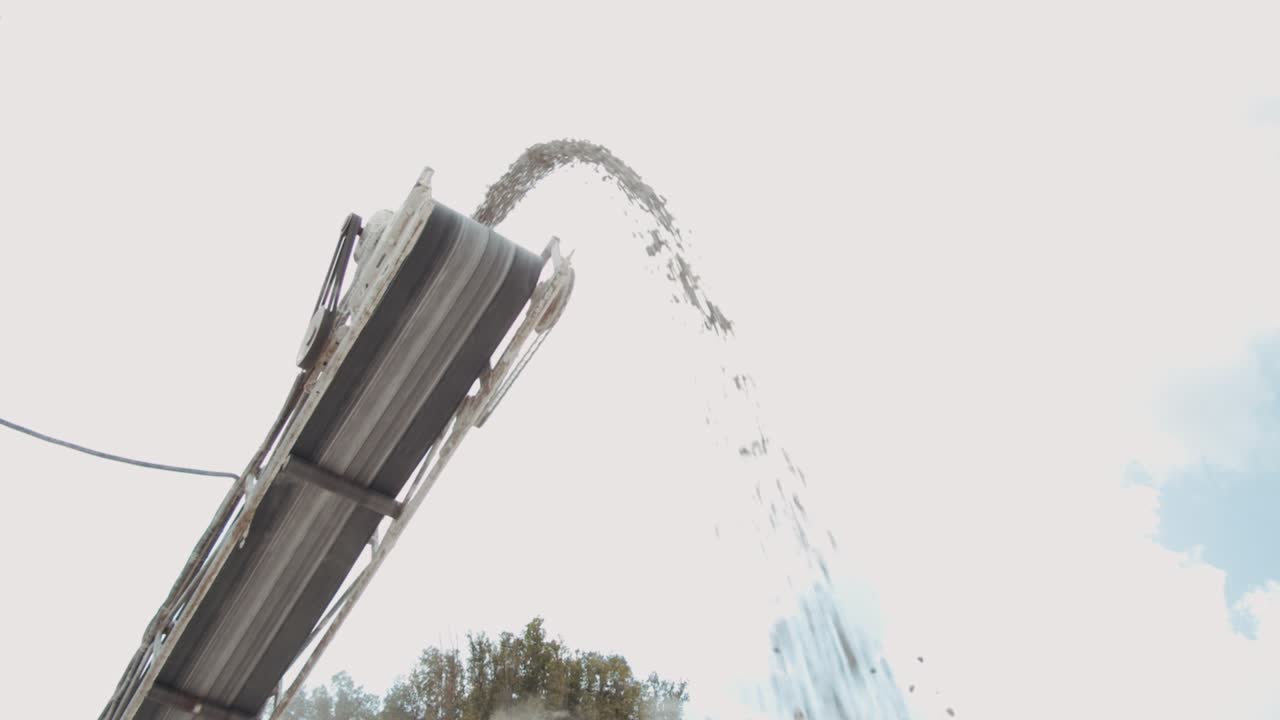 un disparo desde el ángulo bajo en el que las piedras de la trituradora de piedra caen al suelo. video de stock.