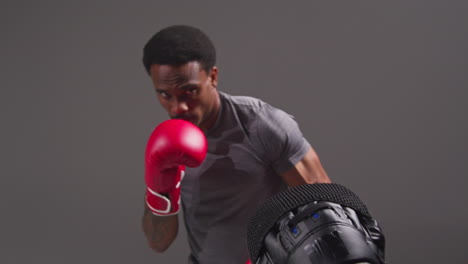 Studio-Shot-Of-Male-Boxer-Sparring-Working-Out-With-Trainer-Wearing-Punch-Mitts-Or-Gloves-Practising-For-Fight-10