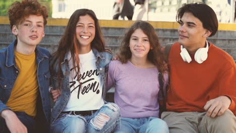 a group of teenage friends of two girls and two boys look directly into the camera and smiles