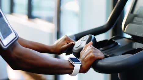 fit woman with smartphone exercising on exercise bike