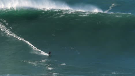 cámara lenta de un surfista de olas grandes montando una de las olas monstruosas más grandes en nazaré, portugal