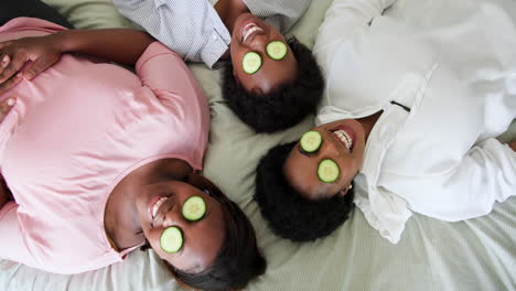 at home, female friends having spa day with cucumber slices on eyes