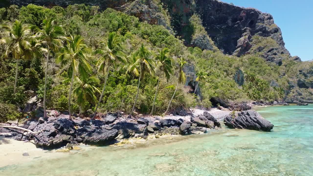 Ripresa con drone di un turista che cammina sulle rocce lungo la spiaggia tropicale di Playa Fronton e il mare cristallino dei Caraibi in estate