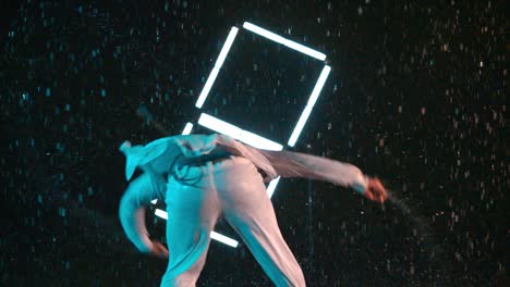young black african-american performing capoeira dance kicks, indoor rain effect