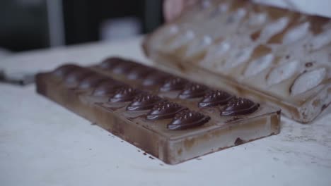 manos abiertas molde de chocolate, revelando caramelos de chocolate elaborados