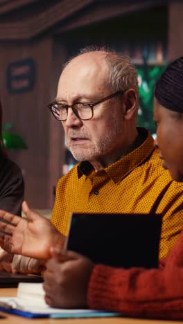 vertical video mature diverse colleagues writing notes and ideas in campus study room