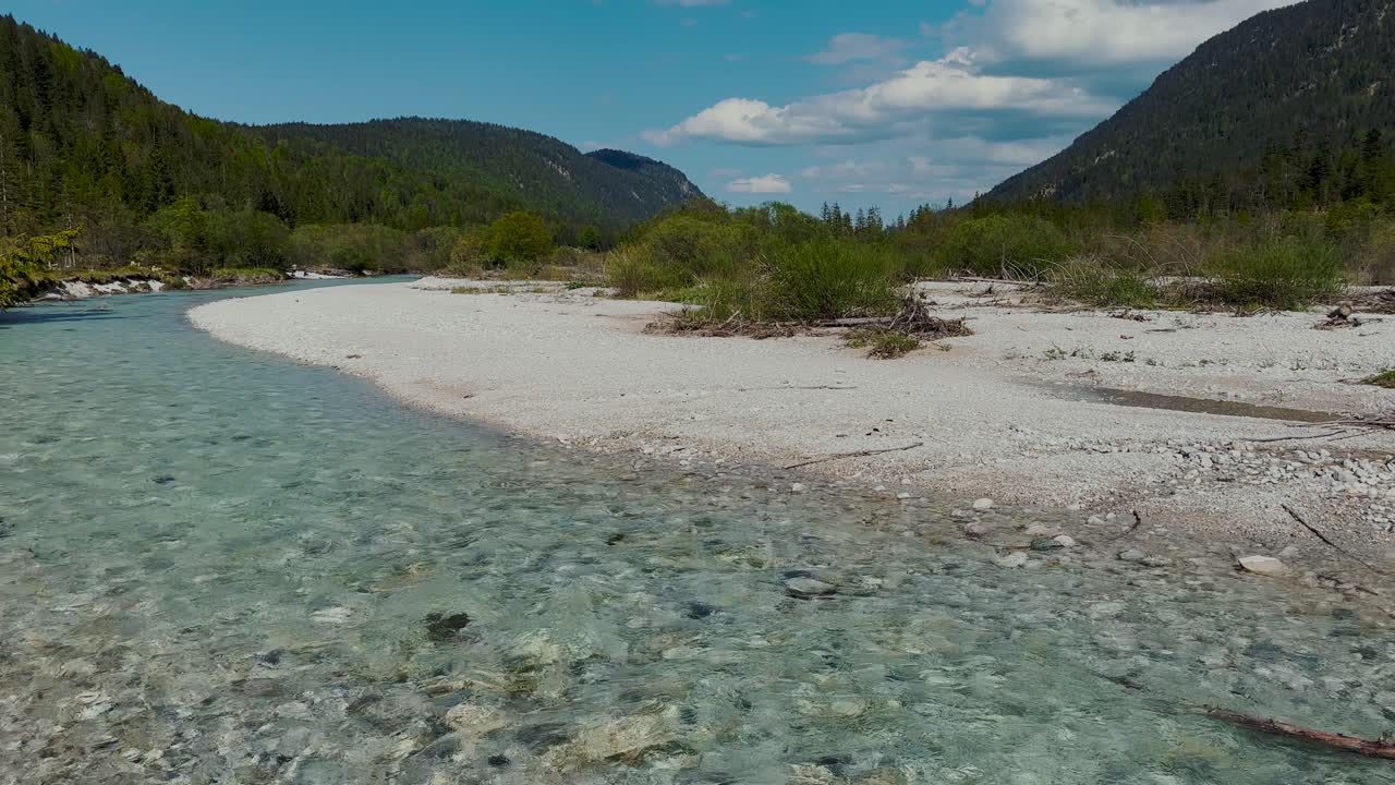 Crystal clear turquoise Isar river with white pebble beach and mountains, Bavarian Alps, Germany