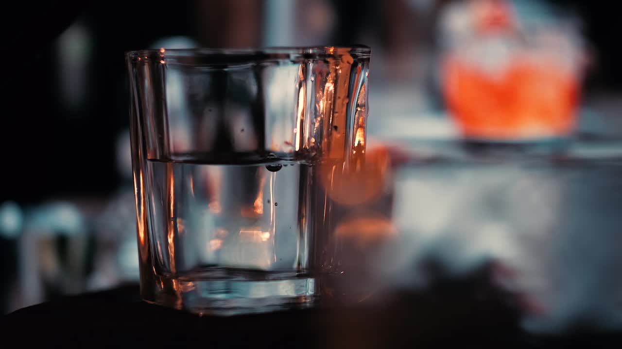 4k bebida épica en el bar con el camarero en el fondo con bokeh de mal humor y iluminación