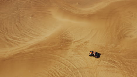 dune buggy all terrain vehicle driving through arid desert near dubai, aerial