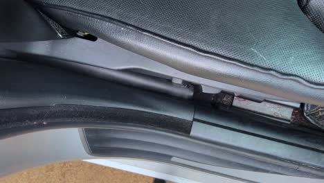 aspirando los pisos sucios del coche y los asientos de cuero negro interior empujando la manguera delgada en el espacio estrecho entre la puerta y el asiento