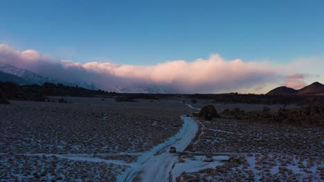 vehicles driving on scenic road in snow at winter in alabama hills, california. aerial drone