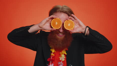 hombre turista guapo poniendo media naranja en los ojos, estilo de vida vegetariano, vitaminas para la salud