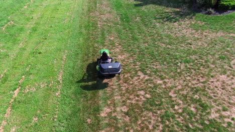 young hispanic woman mowing lawn on tractor cutter