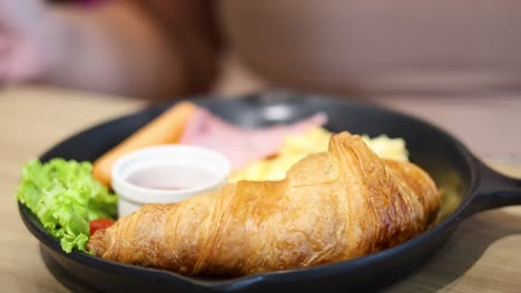 comiendo un croissant con los lados del desayuno