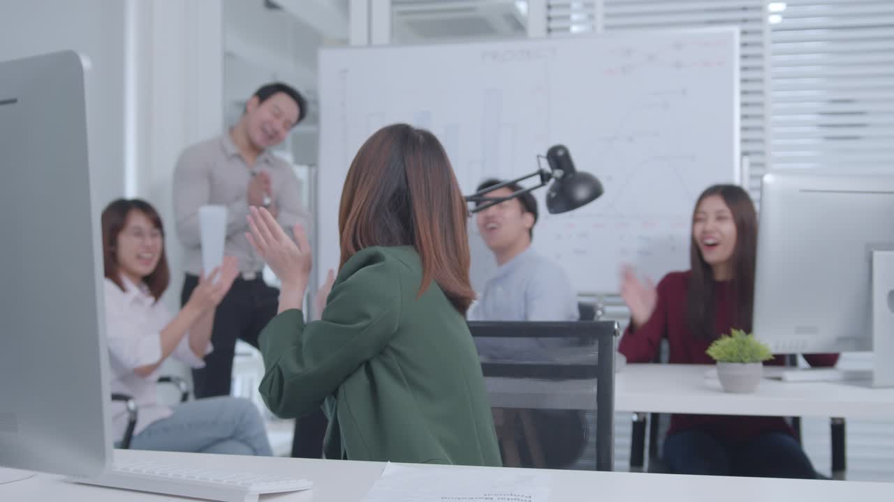 오피스 테이블에 앉아있는 흥분한 아시아 사업가 여성은 성공적인 프로젝트, 직업 승진을 축하하는 팔을 들어 올렸습니다.