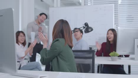 오피스 테이블에 앉아있는 흥분한 아시아 사업가 여성은 성공적인 프로젝트, 직업 승진을 축하하는 팔을 들어 올렸습니다.