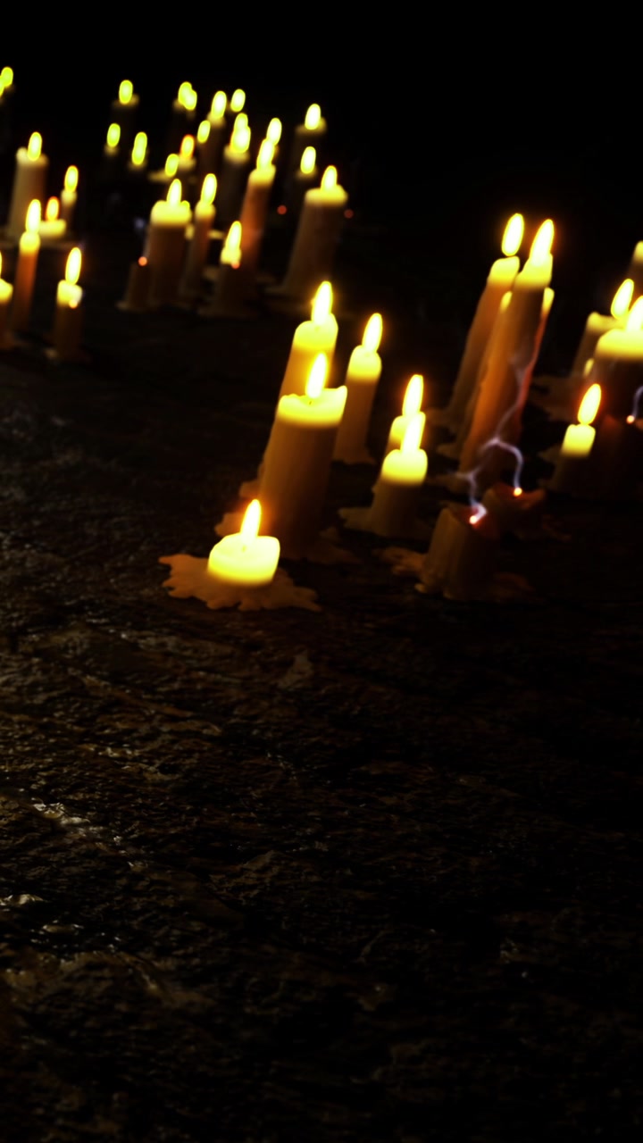 Candele accese a terra in uno spazio buio durante un raduno notturno.