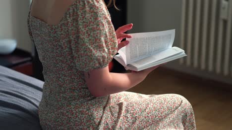 una chica joven en un vestido lee un libro en la cama