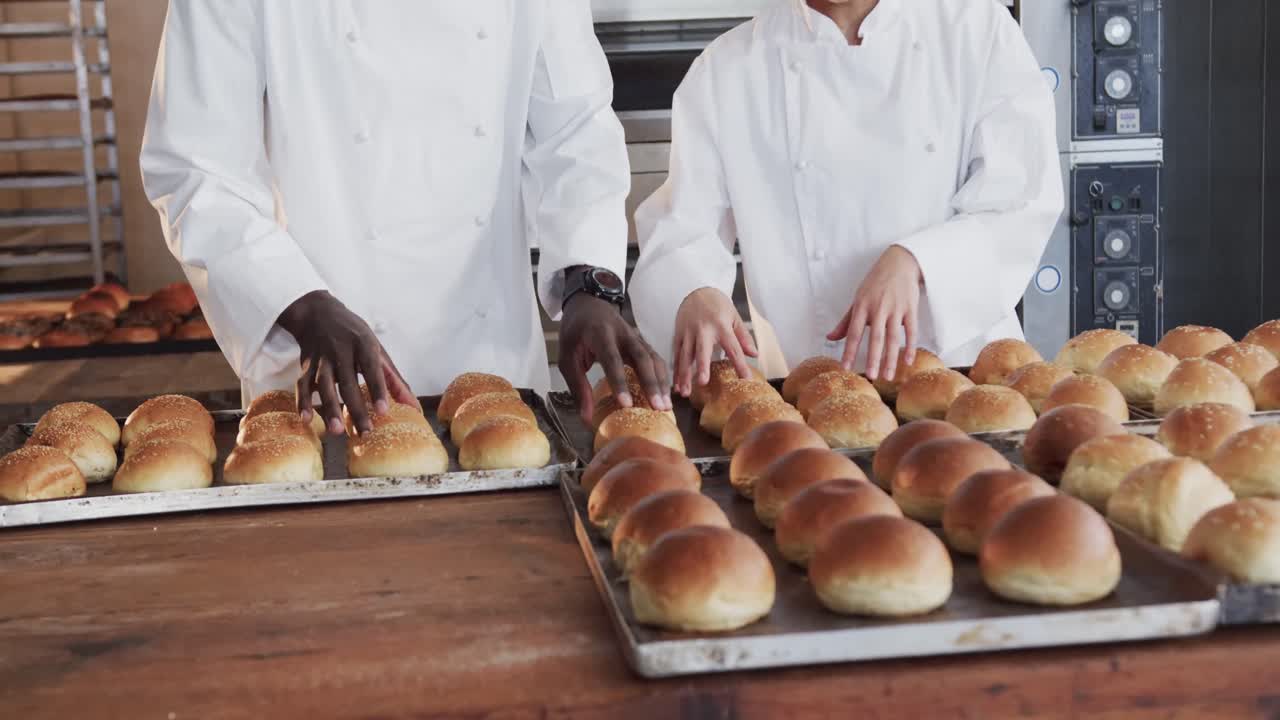 Felici fornai di diverse etnie lavorano nella cucina della panetteria, contando i panini freschi al rallentatore.
