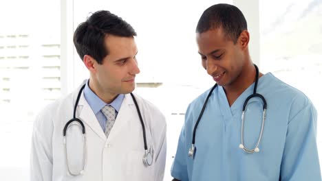 Two-medical-workers-looking-over-file-on-clipboard