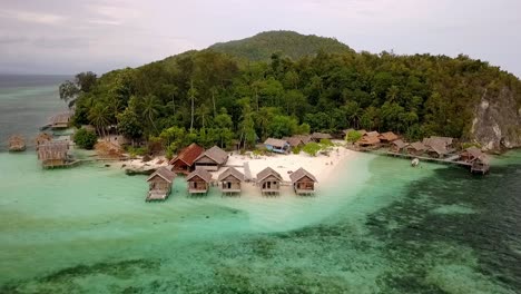 resort with overwater bungalows in the raja ampat island chain in indonesia , aerial circle around shot