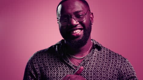 handsome afro guy flirting on pink background. african man making kiss in studio