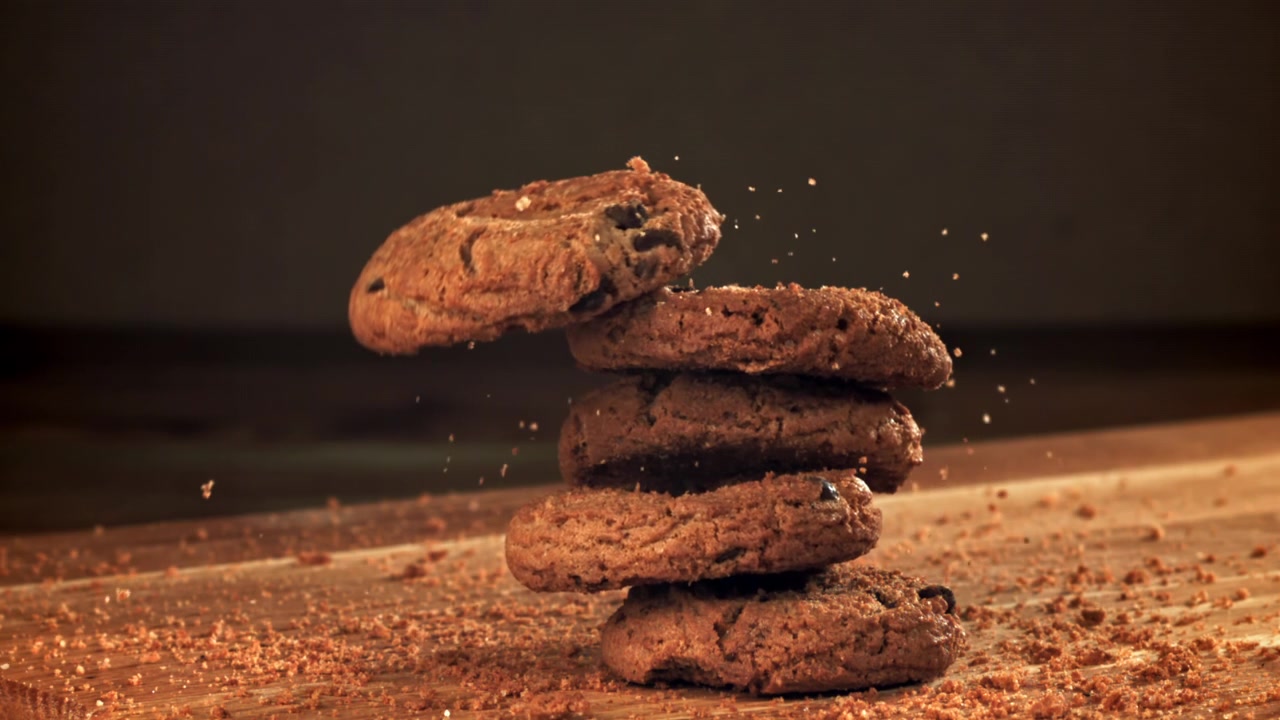 Slow Motion of Chocolate Chip Cookies Falling and Stacking on a Wooden Table