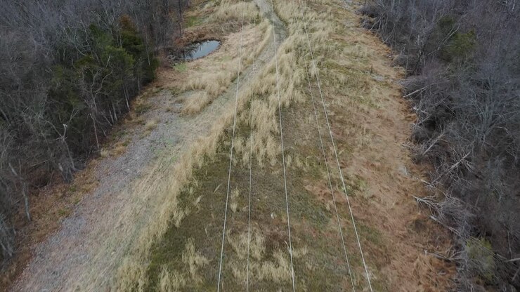 Dolly shot down the lines of electrical transmission structures in rural Kentucky overlooking a large Kentucky river valley vista with large ceramic bell insulators and thick conductors