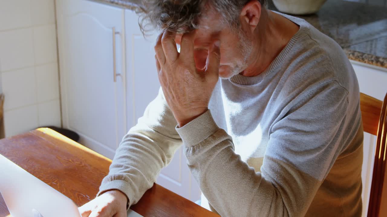 Uomo anziano che usa il laptop in cucina a casa 4k