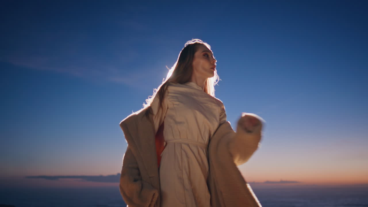나이트클럽에서 춤을 추는 해가 지는 바다 해변에서 가까운 사진. 혼자 춤을 즐기는 여자