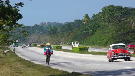 Old-cars-move-along-a-rural-highway-in-Cuba