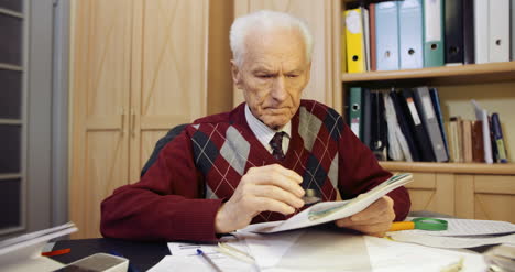 senior businessman reading contract with magnifying glass