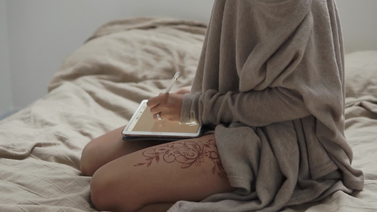 mujer creando arte digital en tableta, tatuaje de henna en la pierna