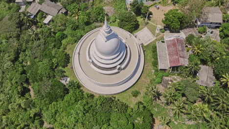 Unawatuna-Sri-Lanka-Aerial-v10-birds-eye-view-flyover-and-around-Japanese-Peace-Pagoda-on-Rumassala-hill,-tilt-up-reveals-breathtaking-jungle-beach-and-ocean-view---Shot-with-Mavic-3-Cine---April-2023