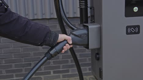 hand taking the plug of an electric vehicle charging station