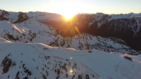 french alps at chamrousse with sunrise between the snowy peaks, aerial flyover approach shot