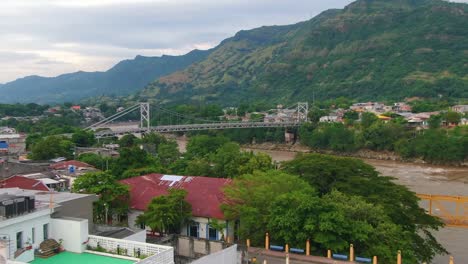 Aerial-dolly-zoom-over-suspension-bridge-crossing-tropical-river-and-mountains