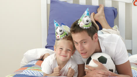 dad and little boy watching a football match in bedroom