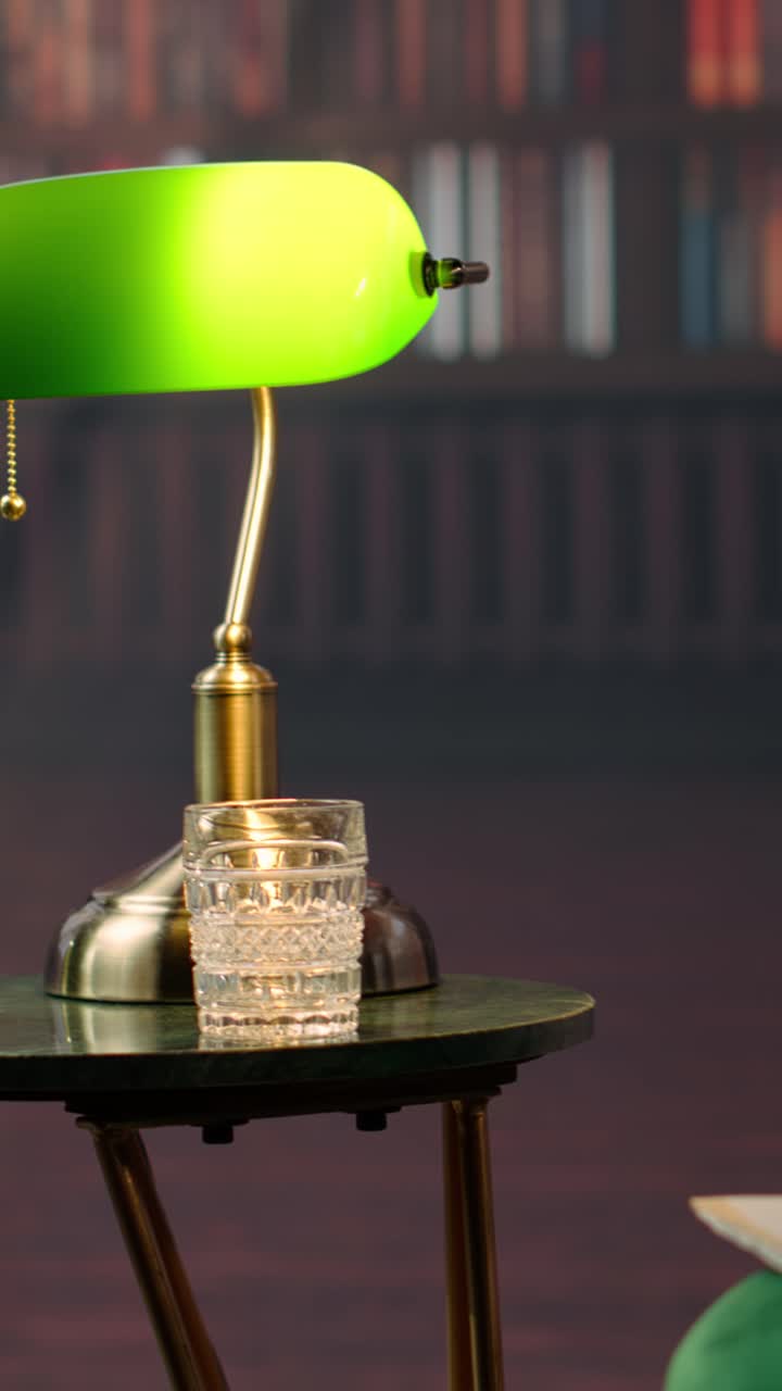 Green Banker's Lamp and Glasses on Table in Library Setting