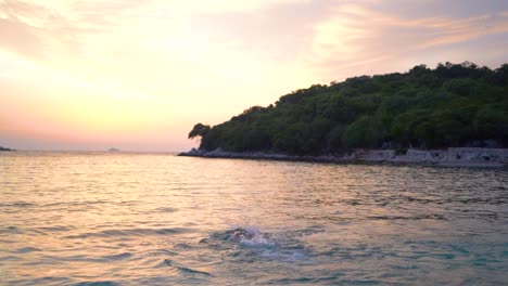 Junger-Mann,-Der-Bei-Sonnenuntergang-An-Einem-Wunderschönen-Strand-Auf-Einer-Tropischen-Insel-Schwimmt