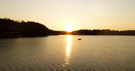 Pescador-Pescando-En-Bote-En-El-Lago-Al-Atardecer