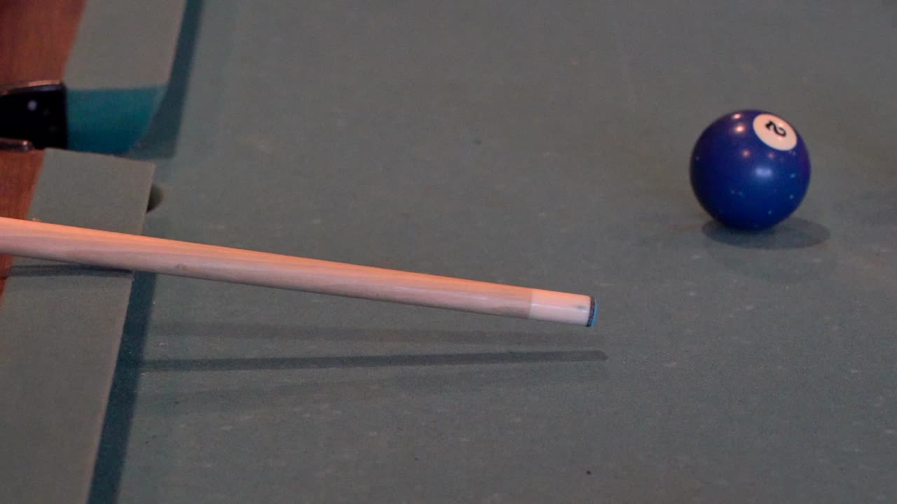 A slow motion view of a pool stick hitting the cue ball