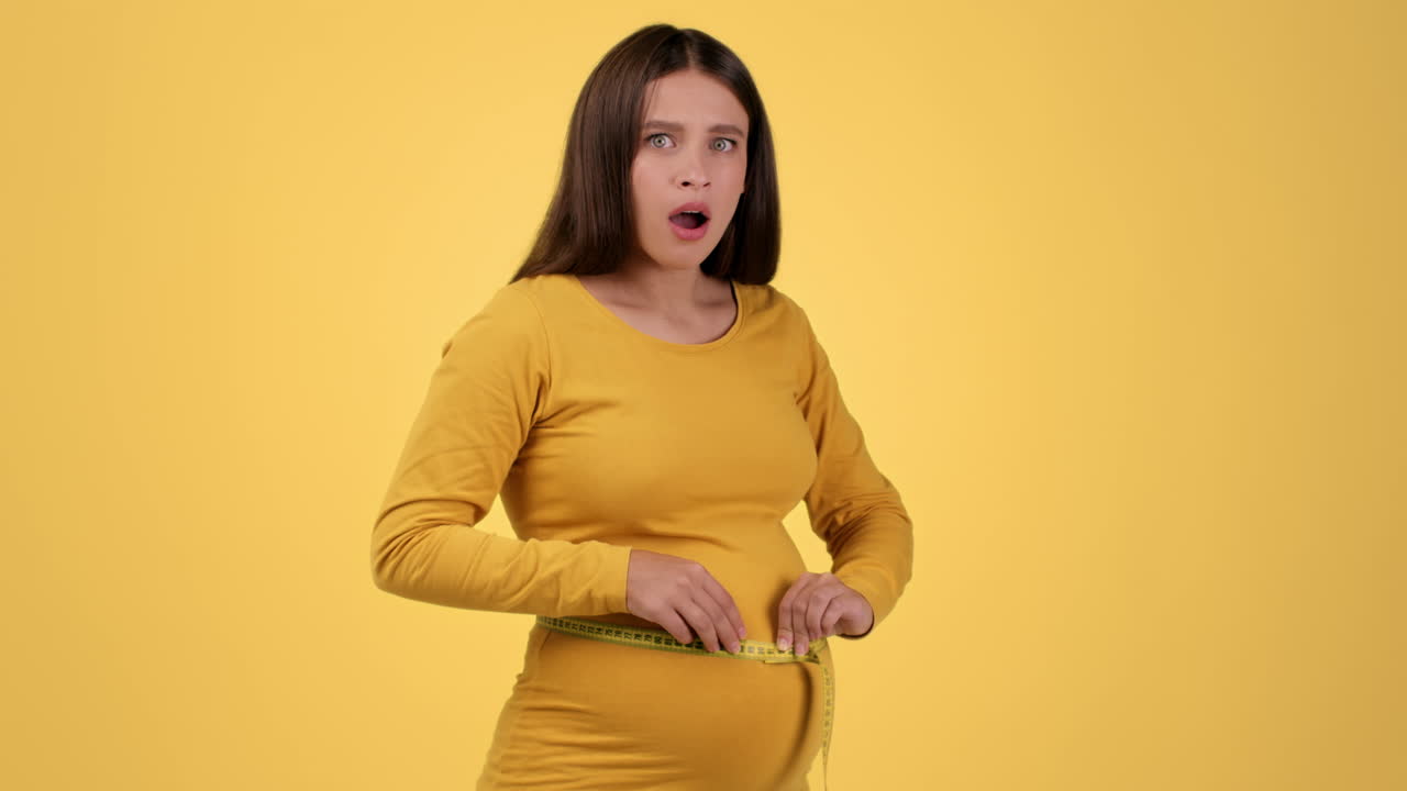 임신 한 여자 가 배 를 측정 하고 있다