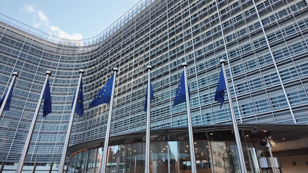 European Commission headquarters with European Union flags waving in slow motion